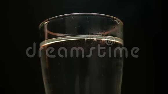 特写将冰块扔进装有水的玻璃杯在黑色背景上隔离视频的预览图