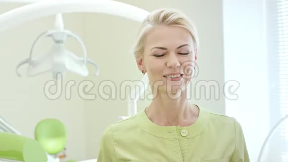 站在牙科办公室的快乐女牙医金发护士对着镜头微笑视频的预览图