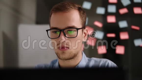 有笔记本电脑的人戴眼镜的年轻人在办公室的笔记本电脑上工作商人上班族男学生工作视频的预览图