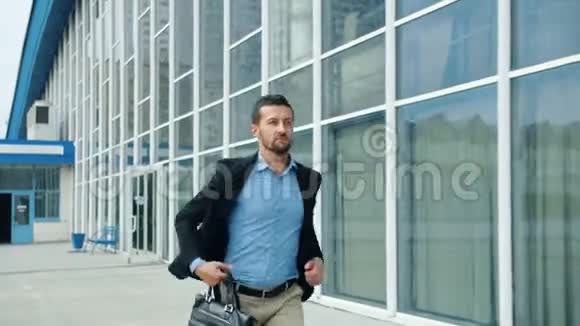 一个英俊的年轻人带着公文包在办公楼里慢悠悠地跑视频的预览图
