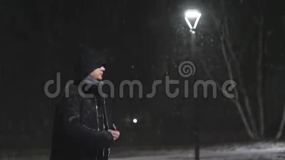 街灯里的那个人那家伙看着他的智能手机在灯的背景下下雪慢动作视频的预览图