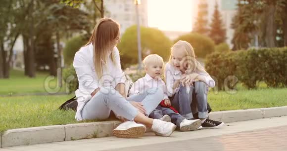 年轻的母亲和金发男孩和女孩在夏季公园玩得很开心视频的预览图