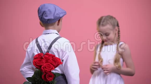 穿着正式服装的小男孩把玫瑰藏在背后送给女孩视频的预览图
