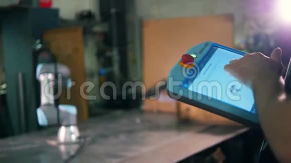 一个人用平板电脑来控制一个工作的机器人手臂视频的预览图
