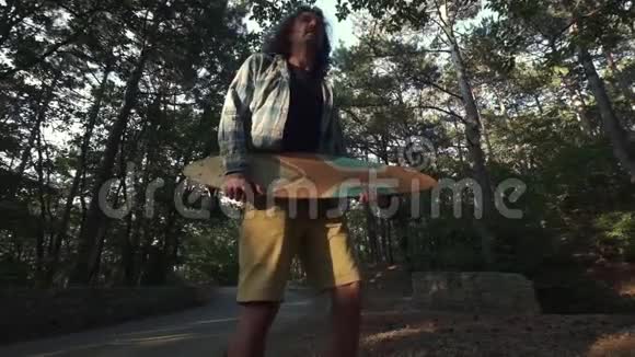 森林里的年轻嬉皮士用长板玩使用长板作为吉他像摇滚明星一样的驼峰乐趣视频的预览图