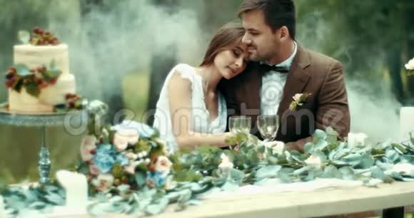 在雾蒙蒙的森林里吃浪漫的晚餐漂亮而敏感的情侣穿着老式的布温柔地拥抱在餐桌上视频的预览图