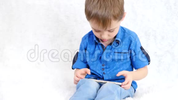 一个小男孩通过互联网玩教育游戏孩子看着智能手机的屏幕笑视频的预览图