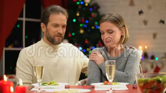 丈夫用舒适的格子布掩护年轻的妻子庆祝圣诞前夜亲戚们视频的预览图