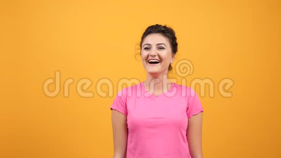 穿着粉红色T恤的年轻女子带着自然的情绪笑着笑着视频的预览图