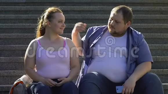 超重的男性拥抱他美丽的女朋友休息在楼梯户外约会视频的预览图