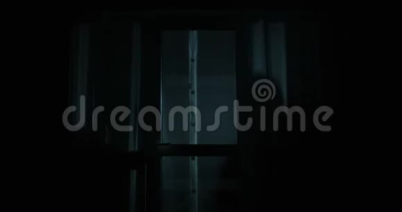 小偷正透过窗户看房子手电筒打开后门在夜深时进入物业视频的预览图
