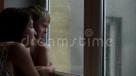母亲和儿子等着有人来看窗外的雨视频的预览图