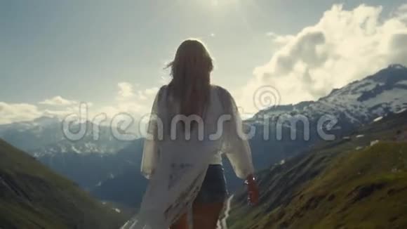 那个运动女孩站在阿尔卑斯山的山顶上她向太阳举手视频的预览图