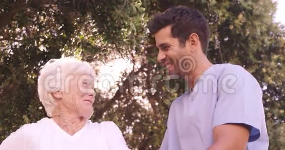 男护士协助一位年长妇女在后院散步视频的预览图
