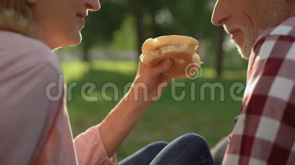 嬉戏的老人和女人在公园放松吃汉堡周末特写视频的预览图