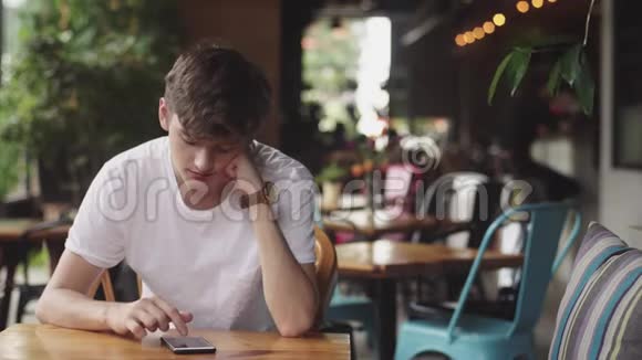 年轻人用手机上网方便触摸在咖啡馆发送短信帅哥在里面聊天视频的预览图