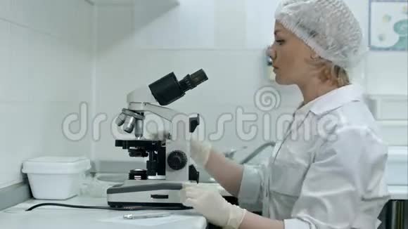 可爱的女性医学研究员在实验室里用显微镜写笔记视频的预览图
