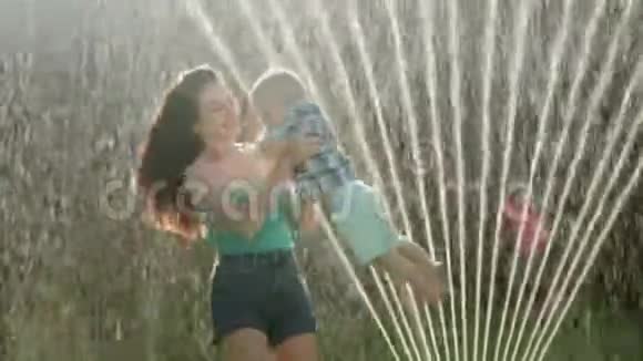 快乐的一家人在草地上的后院玩耍母亲带着孩子们洒水视频的预览图