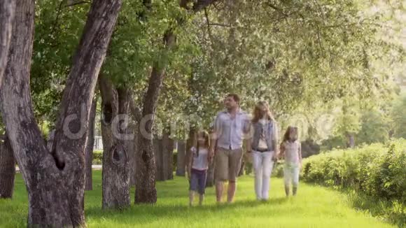 快乐的一家人走在夏天的公园里靠近盛开的苹果树父亲母亲和两个女儿视频的预览图
