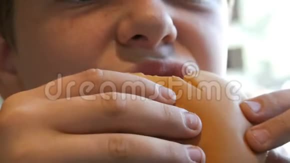 胖男孩吃芝士汉堡的脸特写不健康食品快餐视频的预览图