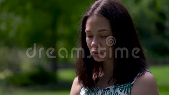 一张悲伤的亚洲女孩脸的肖像背景上的绿树泪水顺着脸颊滚落快关门视频的预览图