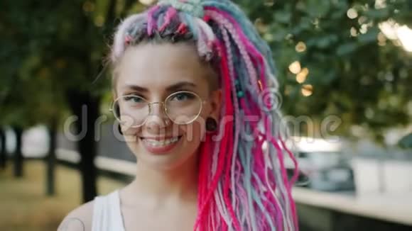 公园里戴着鲜艳的头发和牙套的快乐女人的特写肖像视频的预览图
