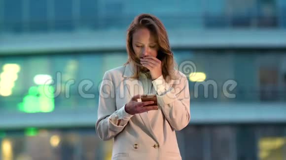 商务女性晚上在城里看手机视频的预览图