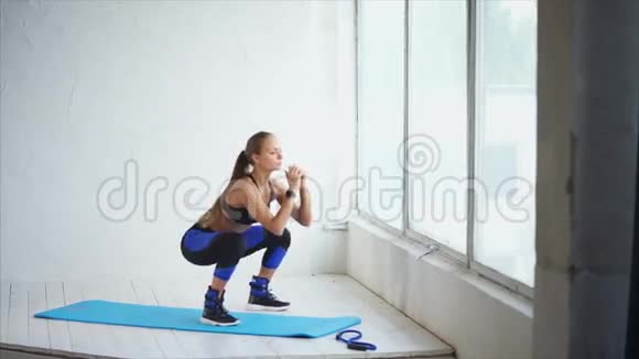 蹲下可爱的年轻女子蹲在健身室里健身房里的场景视频的预览图