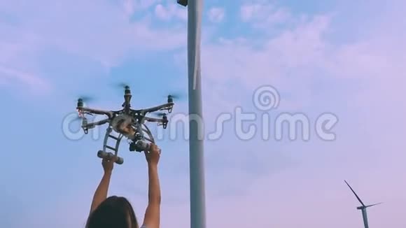 无人机从靠近风力涡轮机的女孩手中起飞动作缓慢视频的预览图