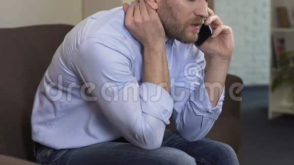 悲伤的男人坐在沙发上和前女友用手机聊天危机视频的预览图
