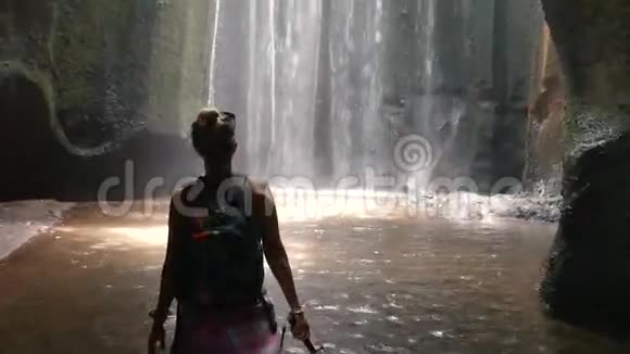 年轻女子张开双臂迎接巴厘岛的瀑布视频的预览图