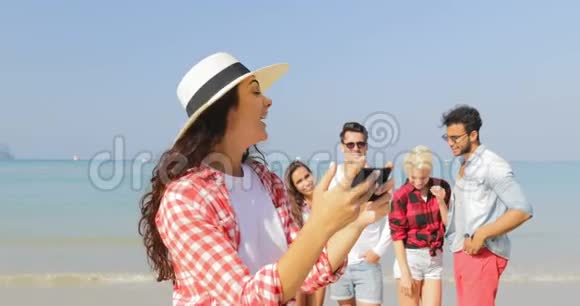 在沙滩上拍照的女孩手机上拍照的人快乐的男人和女人度假的游客视频的预览图