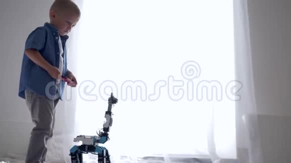 儿童时期的创新技术可爱的小男孩用手机遥控玩机器人玩具视频的预览图