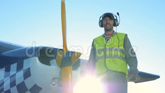 男飞行员站在一架轻型私人飞机附近一个人站在一架小飞机附近看着相机微笑视频的预览图