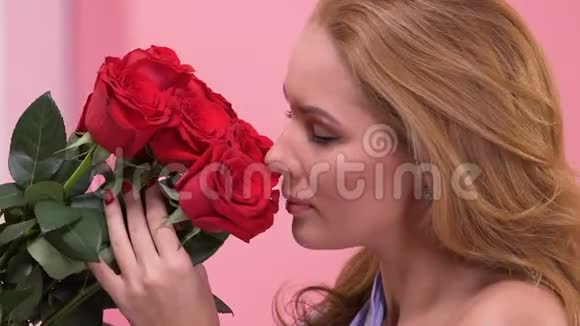 美丽的女人欣赏红玫瑰花束情人节惊喜视频的预览图