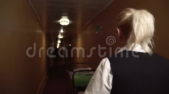 一个女佣把一辆手推车从旅馆的大厅里滚下来迎接一个走过来用手机说话的人视频的预览图