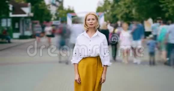 放大了相当成熟的女人站在街上看摄像机的时间间隔视频的预览图
