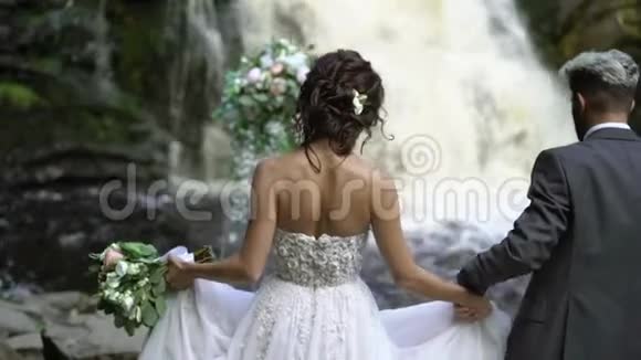 年轻的新婚夫妇在瀑布附近举行婚礼视频的预览图
