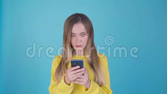 年轻漂亮的女人用智能手机在孤立的背景下发送信息吓得满脸惊讶视频的预览图
