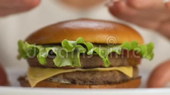 女人咬大快餐汉堡增加额外体重饱和脂肪特写视频的预览图