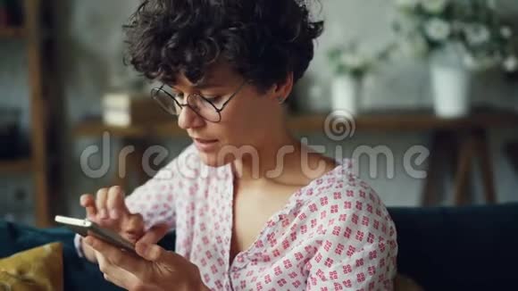 微笑的年轻女子正在拨打电话号码然后在扬声器模式下说话手里拿着智能手机现代视频的预览图