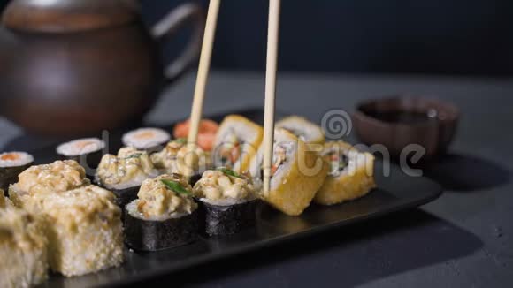 手拿棍子拿寿司概念中国棒寿司卷在一个黑暗的盘子视频的预览图