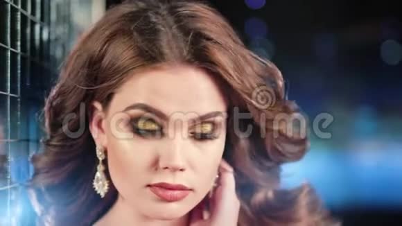 在霓虹灯背景下戴着珠宝闪亮耳环的迷人女模特的特写脸视频的预览图