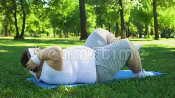胖子在公园里努力锻炼腹肌锻炼强烈的减肥欲望视频的预览图