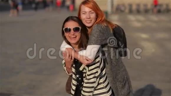两个年轻的女朋友在美丽的城市街头嬉笑散步在度假时捎带着小朋友视频的预览图