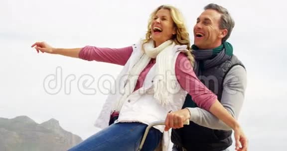 幸福的成熟夫妇双臂张开坐在自行车上视频的预览图