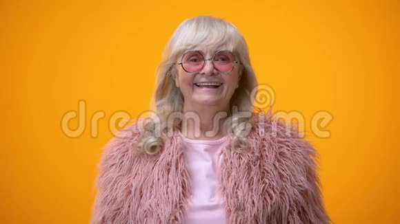穿着粉色外套的有趣的老女人做摇臂手势露出舌头很有趣视频的预览图