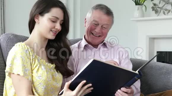 男人与成年孙女一起看相册视频的预览图