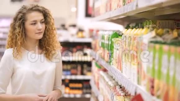 女人在超市里选择果汁在商店里购物视频的预览图