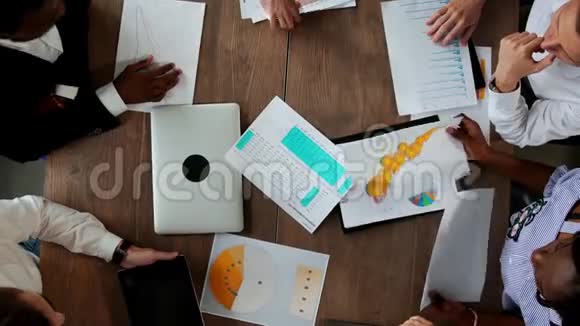 各民族创意经理办公室团队在大办公桌后面的俯视图视频的预览图